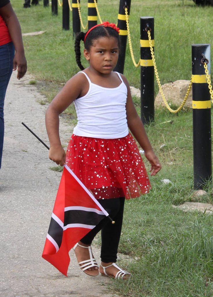 A girl walks with her national flag after viewing the Independence Day parade at Queen's Park Savannah, Port of Spain.