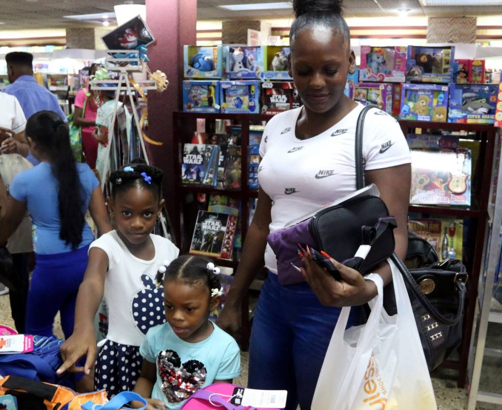 Saturday shopping: Daniella Norton shops with her daughters 
Veronicka Huggings, five, and Claire Huggings, three, at a store on High Street, San Fernando yesterday. Norton said she bought school books long before the month-end. PHOTO BY ANSEL JEBODH