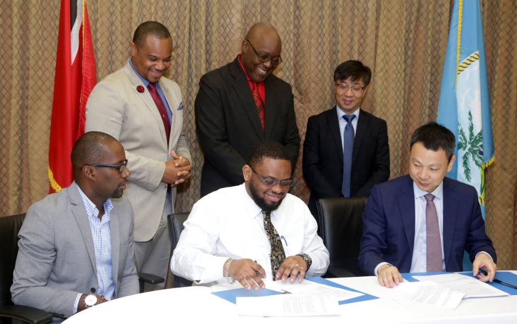 Ritchie Toppin, Administrator in the Division of Infrastructure, Quarries and the Environment, (front, centre) signs a Memorandum of Understanding (MOU) between the Tobago House of Assembly and the China Railway Construction Caribbean Co., Ltd (CRCCC) as executives look on. Looking on are, at right front, Yan Meng, Managing Director (CRCCC); front left, Dunstan Dennon, Advisor to the Secretary, Dunstan Denoon; Back (from left) Councillor Kwesi Des Vignes, Infrastructure Secretary; Kelvin Charles, Chief Secretary of the Tobago House of Assembly; and Mr. Feng Laigang, Vice President, CRCC International.