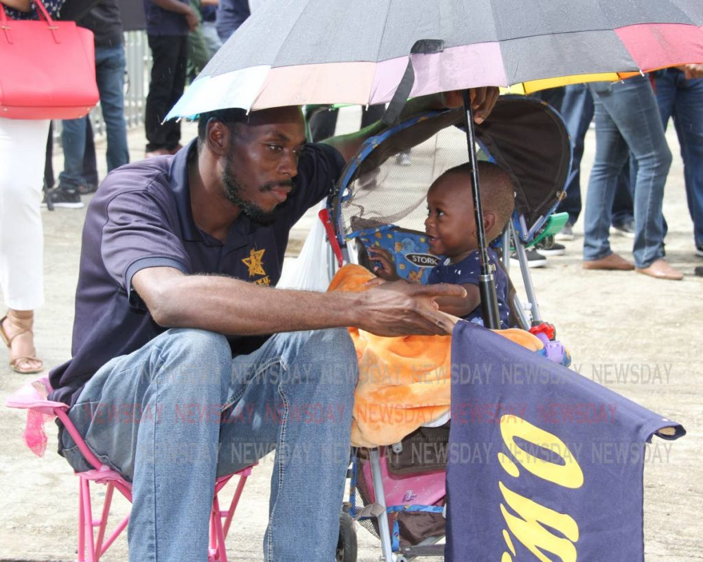 What's our fate?: Petrotrin labourer Daniel George in deep thought as his 11-month-old son, Micah, smiles at him outside the Office of the Prime Minister, St Clair last Thursday when Government told the OWTU it would proceed with the closure of the Petrotrin refinery.  PHOTO BY SUREASH CHOLAI 