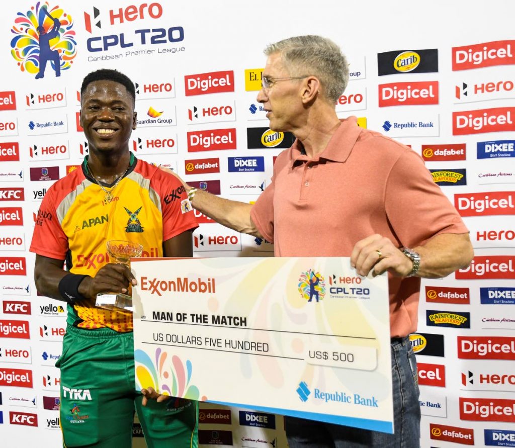 Sherfane Rutherford, left, of Guyana Amazon Warriors receives the man of the match prize from Rod Henson of Exxon Mobile after Guyana defeated Trinbago Knight Riders on Sunday at Providence Stadium in the Hero Caribbean Premier League. PHOTO BY RANDY BROOKS - CPL T20