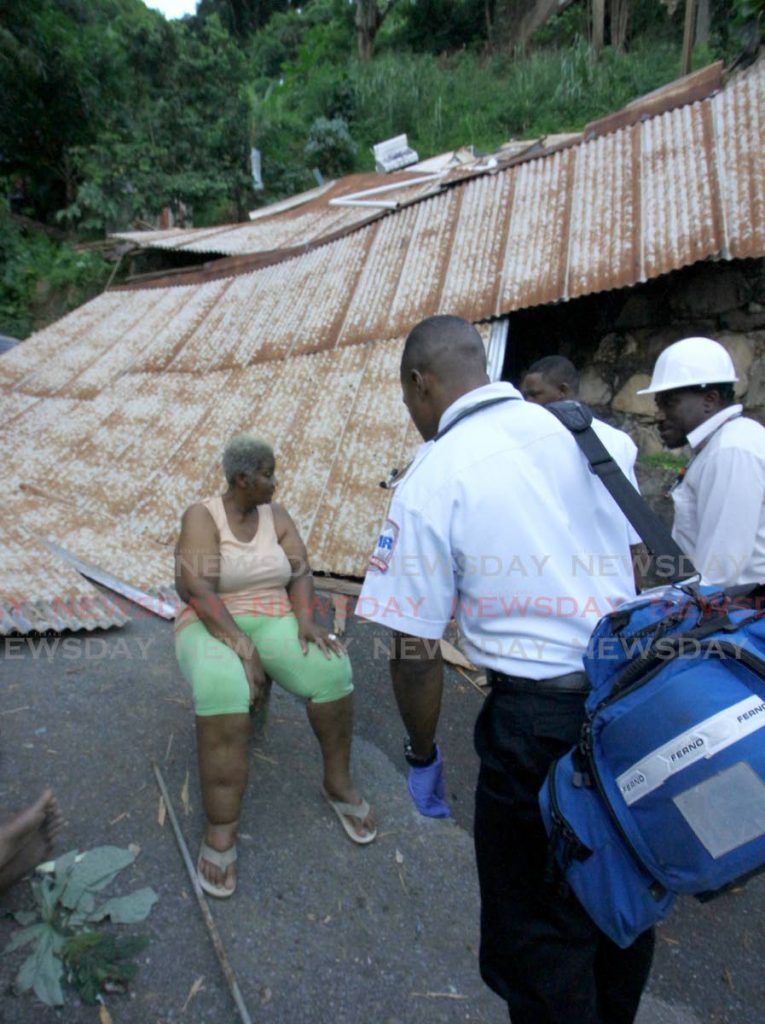 UNHARMED: Great grandmother Viola King speaks to medics in front of the roof of her La Puerta, Diego Martin house which collapsed yesterday. PHOTO BY ROGER JACOB