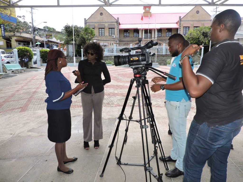 Minority Councillor Dr Faith BYisrael, left, conducts a press conference at James Park, Scarborough. In the background is 
the Tobago House of Assembly Chamber.