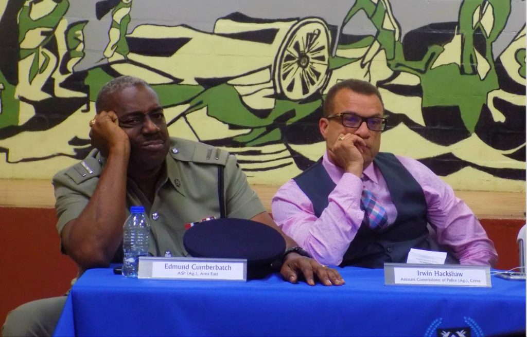 Acting ASP Edmund Cumberbatch, left and ACP Crime Irwin Hackshaw listen to a Trou Macaque resident during Wednesday's town hall meeting at the Trou Macaque Community Centre in Laventille