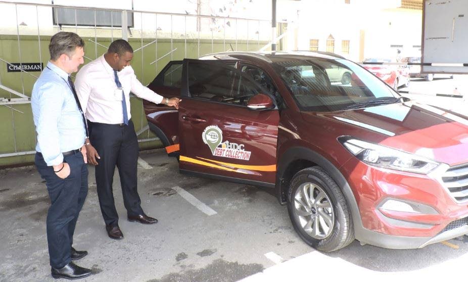 ALL SET: Officials from the Housing Development Corporation (HDC) inspect one of the vehicles to be used in the corporation’s debt recovery drive. PHOTO COURTESY THE HDC