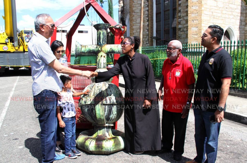Holy Trinity Dean, The Rev Shelly-Ann Tenia thanks contractor Junior Sammy, alongside his daughter Shivonne and grandson Rai, after a crew from his company removed a damaged orb and cross from the church in Port of Spain today. At right, are Sammy's son Shaun and IRO president Dean Knolly Clarke, former rector of the cathedral.
