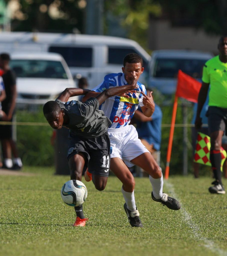 Naparima’s Nathaniel Perouse(L)  tries to hold off  his opponent from CIC player during SSFL action at St Mary’s grounds yesterday.
