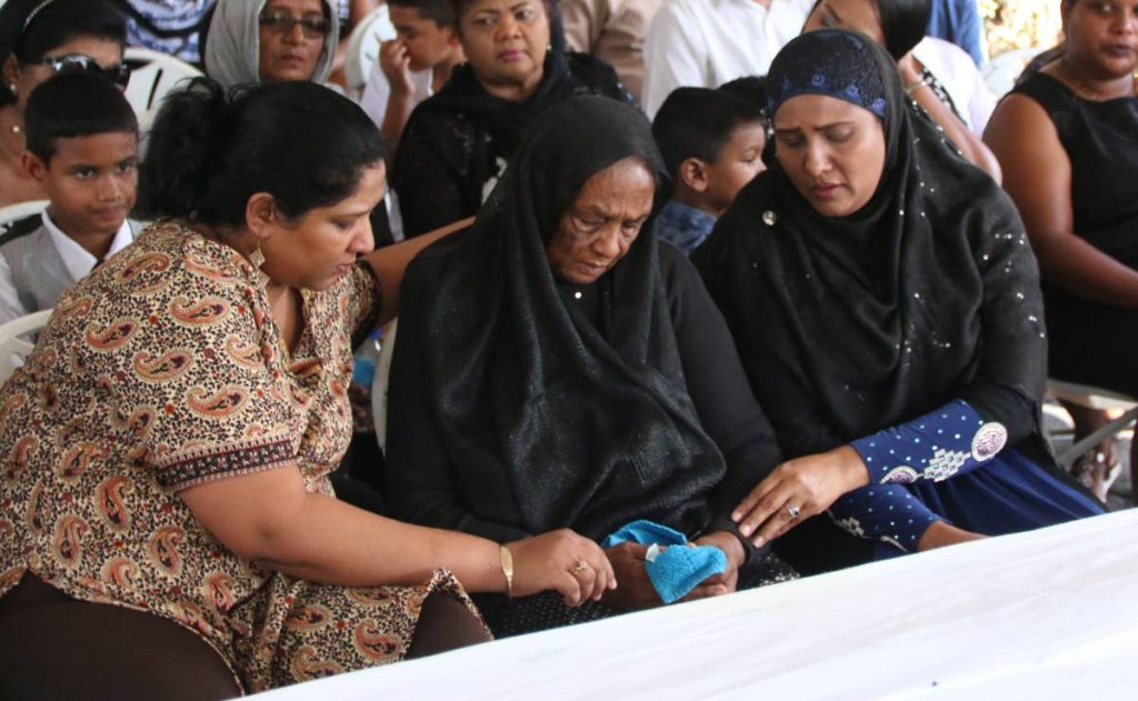 Rosie Singh, centre, is comforted by two of her daughters Sherry Badree, left, and Isha Mohamed at her husband Dilip Singh’s funeral which took place at a relative’s home in San Francique yesterday. Dilip died in a fire in which Rosie suffered burns trying to save him. PHOTO BY ANSEL JEBODH