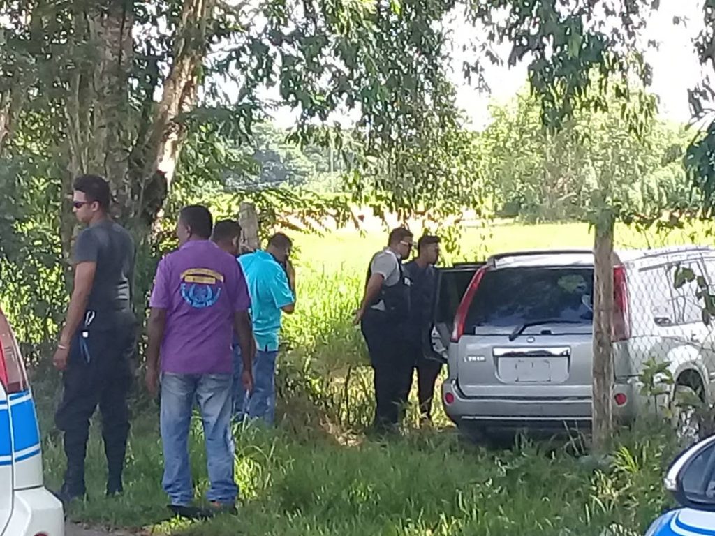 Officers of the Caroni Police Station examine a silver Nissan X Trail with missing license plate numbers which was believed to have been used as the getaway vehicle in a St Helena bank robbery yesterday.