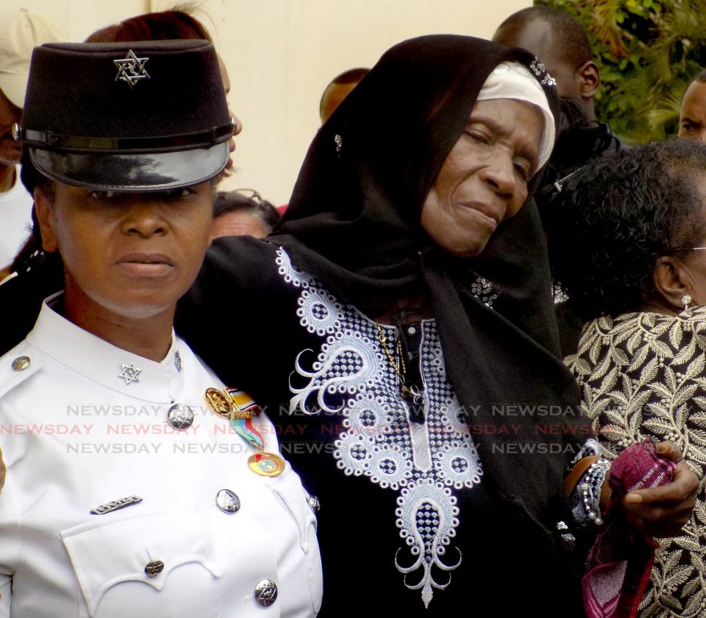 A Woman Police Constable carries Margaret Garcia, the mother of Cpl Ian Hamilton for his funeral at the St Mary's Anglican Church in Tacarigua yesterday. Photo Shane Superville