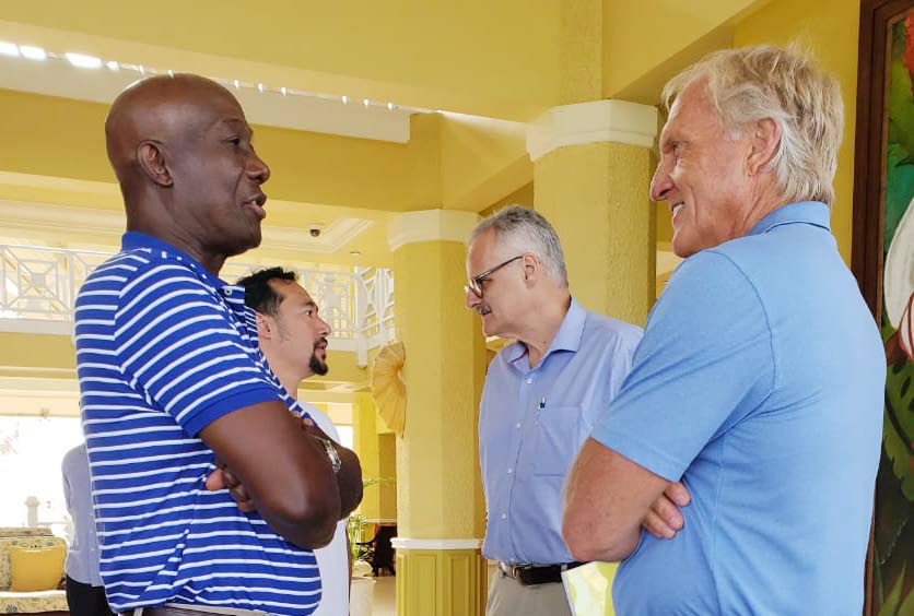 PM Dr Keith Rowley, left, chats with Sandals consultant and pro golfer Greg Norman. In background, Sandals CEO Gebhard Rainer engages Communications Minister Stuart Young.