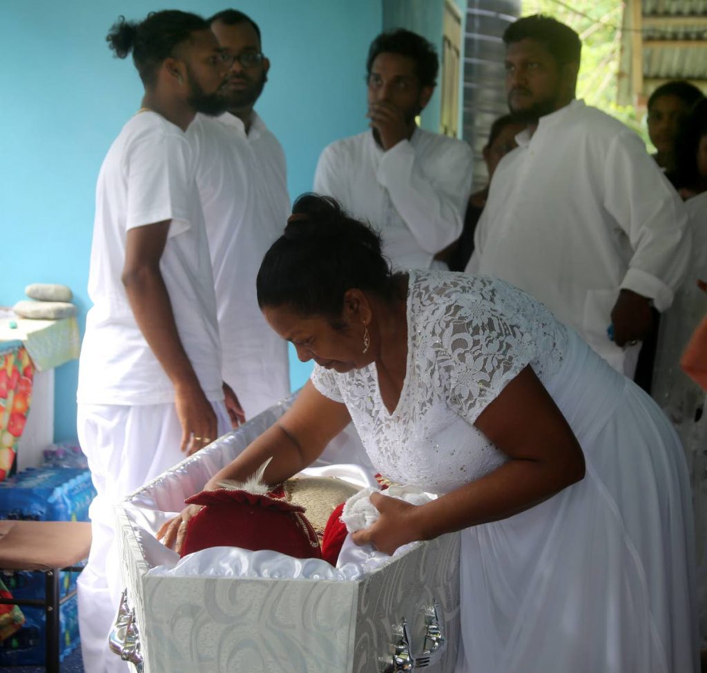 Savatri Roopchand caresses her son Shivan Premnath Ramdhanie one last time during his funeral at a relative's home in Gran Couva yesterday. Ramdhanie, a guitarist with Bon Cane, was shot dead last Wednesday. PHOTO BY VASHTI SINGH
