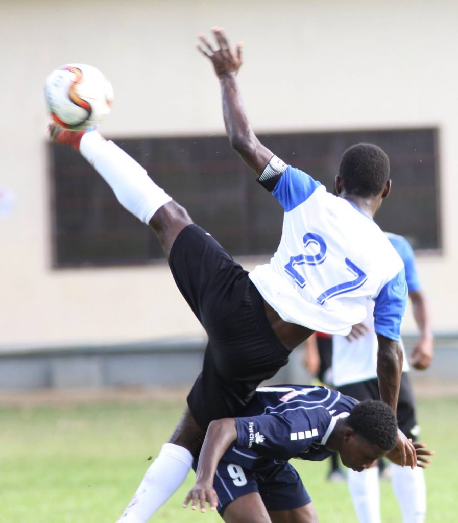 Randy Harris of QRC leans over on the back of Presentation San Fernando’s Darnell Hospedales as he vies for a ball during yesterday’s SSFL Premier Division game at the QRC Ground, St Clair.