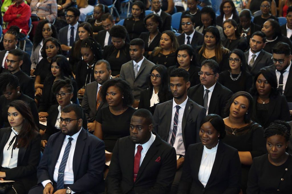 ATTENTIVE: A cross section of the law graduates listen to the various speakers at the graduation ceremony held at the UWI sport and physical education centre on Saturday.   PHOTO BY AZLAN MOHAMMED