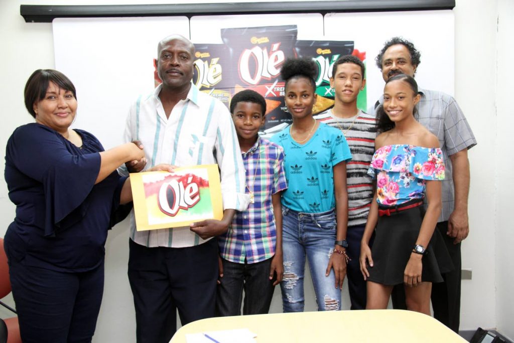 Michelle Agostini Sunshine Snacks Brand Manager,left,  presents a cheque for 50 uniforms to the Silver Bullet Athletic Club head coach Kenrick Williams,2nd left, while club members Jemell Boatswain, Camille Lewis , Reuel Lewis , Christimarie Maharaj and assistant coach Chris Maharaj look on at the ABIL Head Office, San Juan. Photo by Sureash Cholai