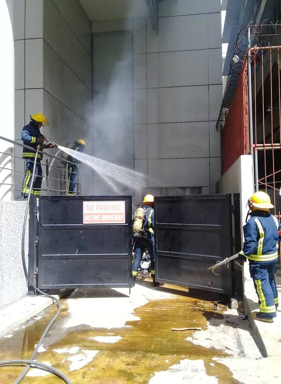 PUTTING IT OUT: Fire officers from the Fire Service Headquarters at Wrightson Road put out a fire at the dumpster behind Education Ministry offices at Edward Street, Port of Spain. 