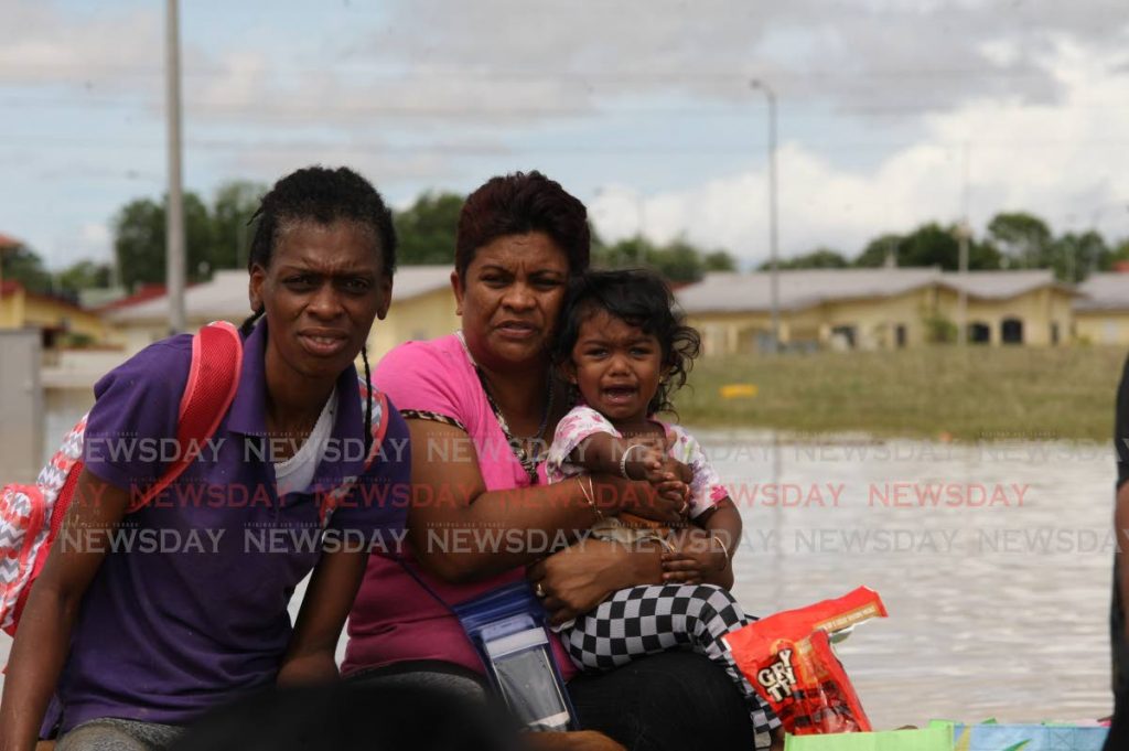 Greenvale residents including a child are taken by boat out of the flooded community in east Trinidad. PHOTO BY LINCOLN HOLDER