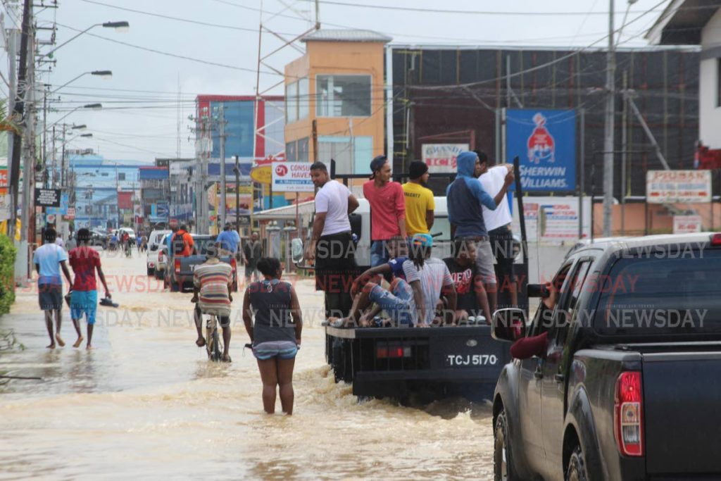 Residents make their way through floodwaters on the main road in Sangre Grande on Saturday. PHOTO BY ENRIQUE ASSOON