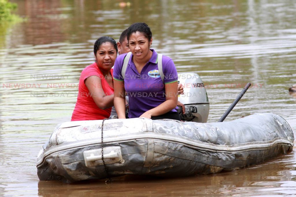 Mayaro residents use a dinghy to get out of floodwaters. PHOTO BY ANIL RAMPERSAD 