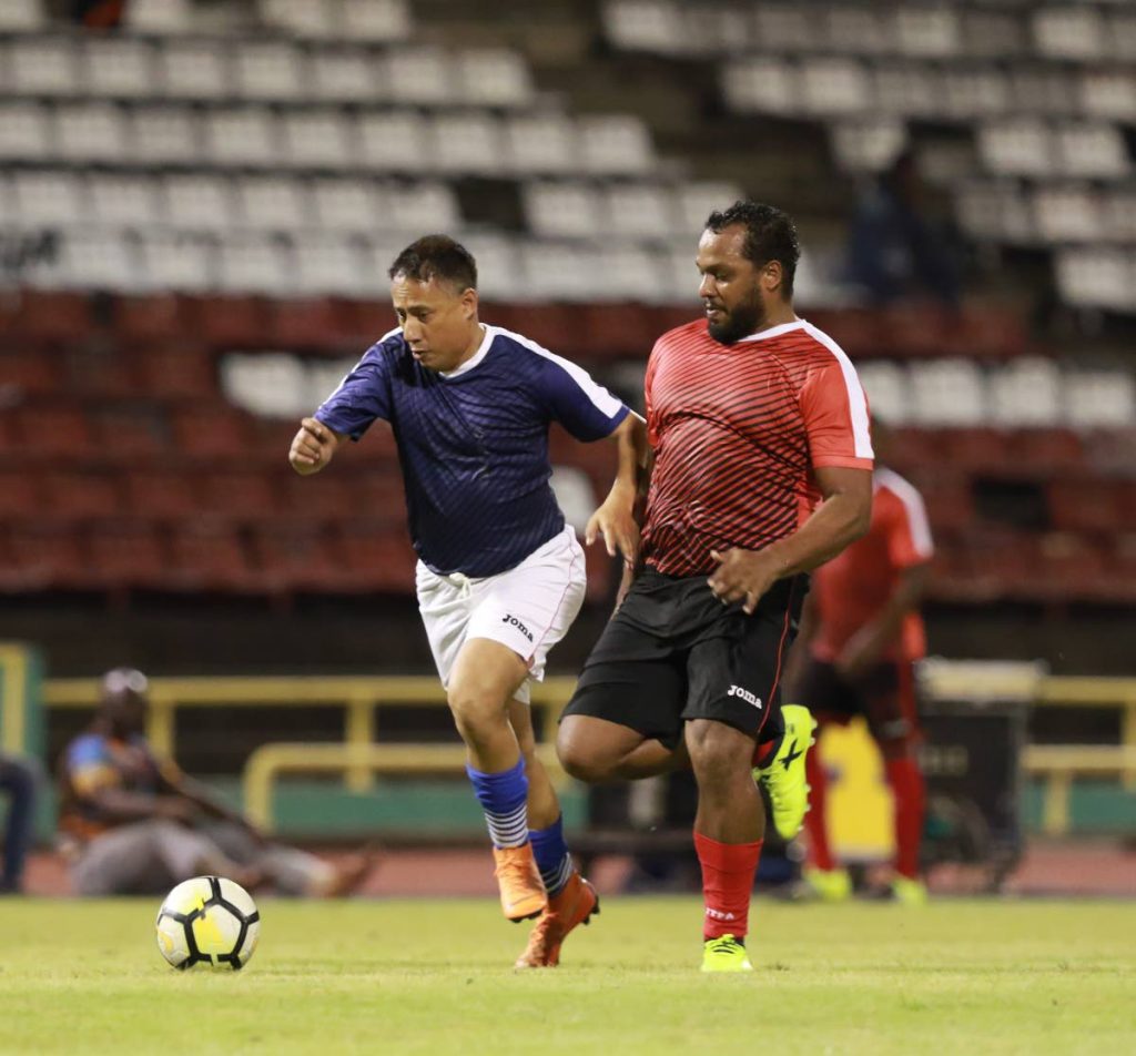 Commissioner of Police Gary Griffith (left), of Team Relief, tries to run past an oppenent during the ‘Football For a Cause’ match at the Hasely Crawford Stadium,Mucurapo, on Friday night.