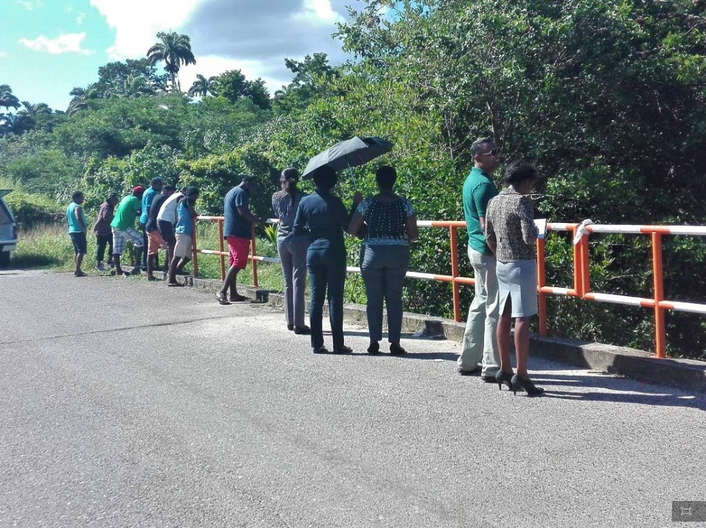 BODY BELOW: Curious onlookers gather at a bridge in Moruga yesterday after a man's body was found floating in the river below. File Photo by Lincoln Holder