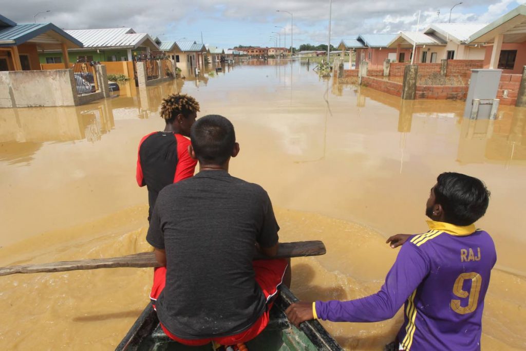 In this October 20 photo, Anil Boodhan and Avinash Deonarine and other residents check for persons needing rescuing following devastating floods in the HDC Greenvale housing development, La Horquetta. Photo by Lincoln Holder 