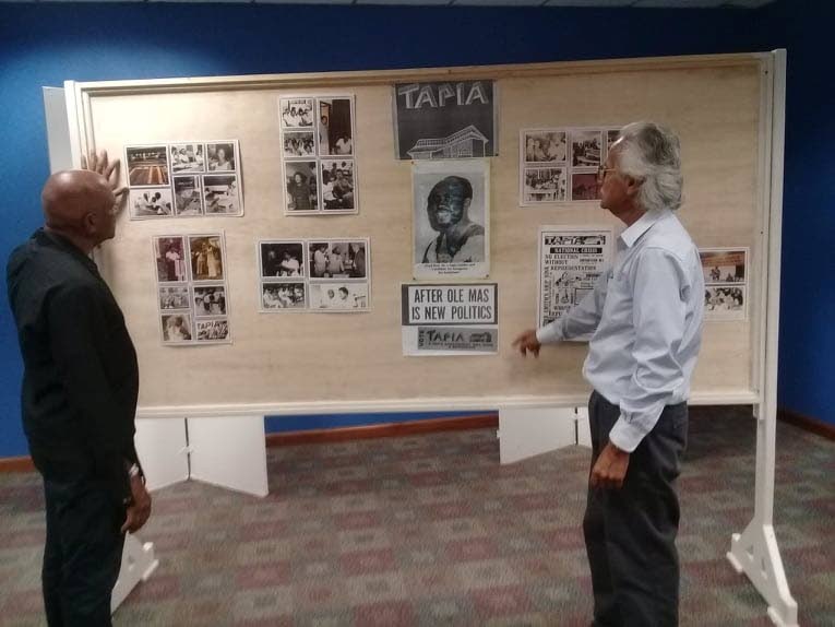 LOOKING BACK: Tapia House founding member Lloyd Taylor (left) and Tapia House member Ishmael Samad look at a display celebrating 50 years of the political movement at the National Library, Port of Spain. 