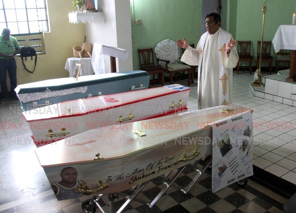 PRAY FOR THEM: Fr Nathasingh officiates yesterday at the Corpus Christi RC Church, at the funeral of three shot dead by police. PHOTO BY SUREASH CHOLAI