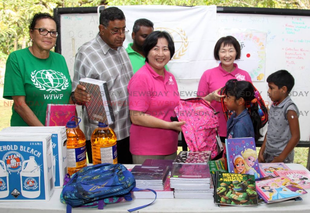 WFWP representative Nobuko Sasaki presents a bag and school supplies to a girl, whose family was affected by flooding on October 19-20, at North Oropuche Government Primary School, last Saturday. From left is WFWP president Princes Lee Keith and Sangre Grande Regional Corporation chairman Terry Rondon. NGOs and bookstores are helping children return to school with new supplies. PHOTO BY ANGELO MARCELLE
