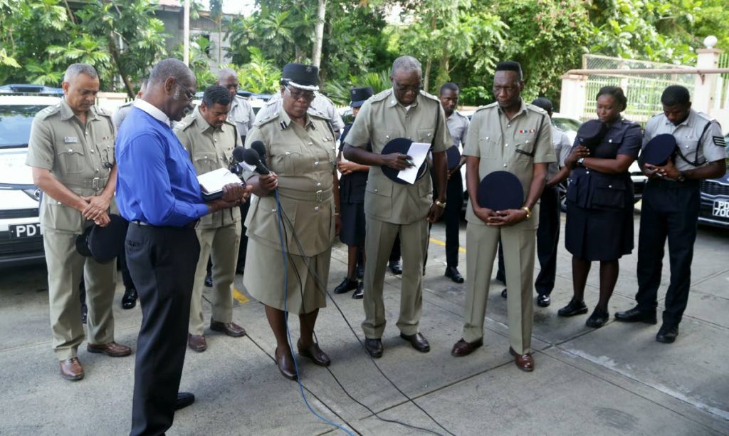 Archdeacon Phillip Issac, front left, prays during the blessing of the new Emergency Response patrol vehicles of the TTPS on Friday in Scarborough. The senior officers standing in front row (from left) are ACP Sharon Blake-Clarke, Snr Supt Jeffrey George and Supt Sterling Roberts. 