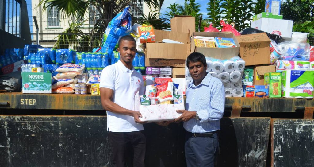 Petrotrin Executive Director Reynold Ajodhasingh (right) hands over relief supplies to a representative of the TT Red Cross Society. 