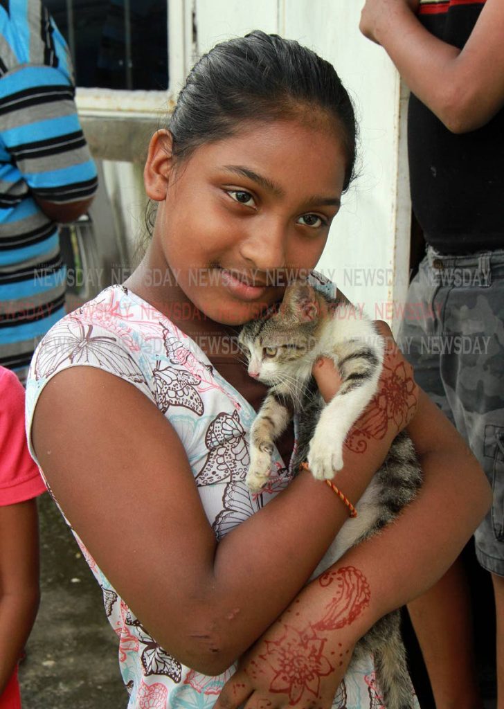 Michelle Rampersad, 10, hugs her pet cat after both of them are lucky to be alive when their family home was destroyed by fire on Divali Night at Baksh Settlement, Mc Bean, Couva. PHOTO BY ANIL RAMPERSAD.