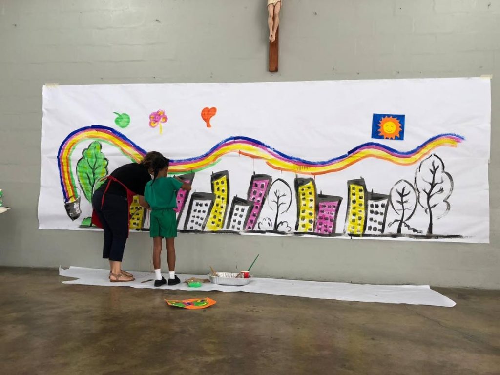 Art teacher Annalise Dos Ramos and student Amaia Thomas paints a mural to depict Maybe Something Beautiful, based on the book by F Isabel Campoy and Theresa Howell, at Holy Faith Preparatory School (St Bernadette’s), St Ann’s.