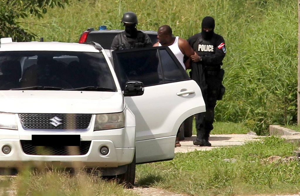 HELD: Police put a man into a car after searching a house at Macaya Trace, Munroe Road, Cunupia yesterday where they allegedly found guns and drugs.