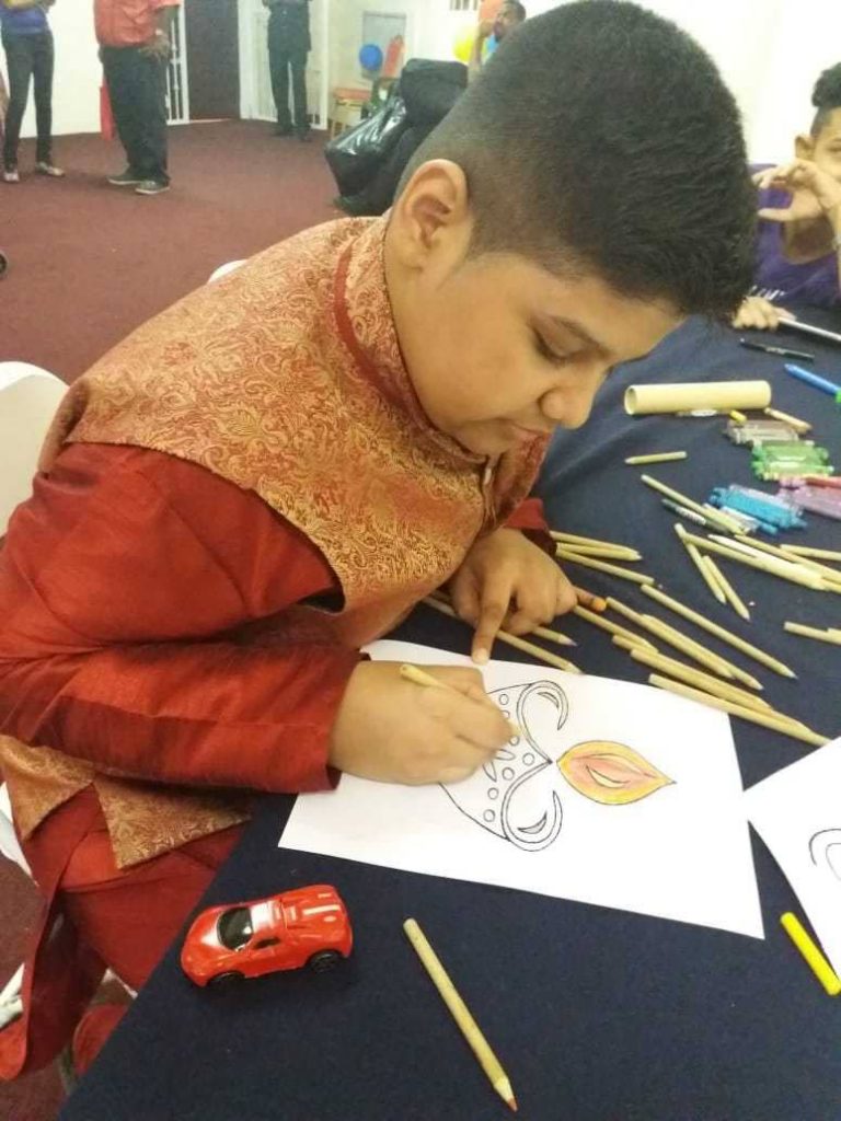 Akash is absorbed in a colouring activity at the Autism Outreach Booth at the Divali Nagar.