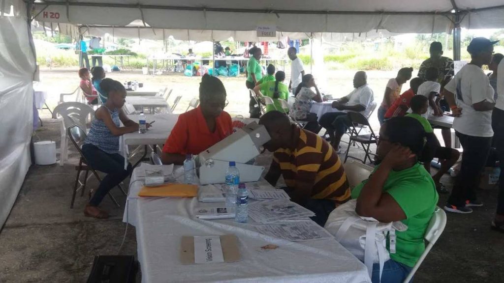 CHECKING UP: Residents of Oropune Gardens, Piarco have their eyesight tested during a health fair in their community on Sunday.