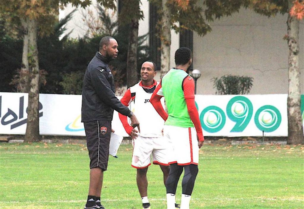 TT coach Dennis Lawrence (left) speaks to his captain Khaleem Hyland (right) and midfielder Leston Paul during a training session in Tehran on Tuesday.