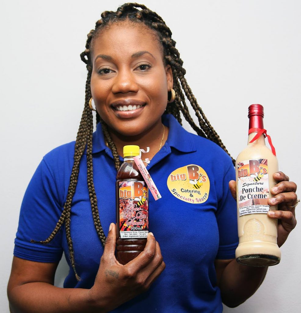 Reeni Bernard with bottles of ponche de creme and barbecue sauce–two products in the Big B’s line. PHOTOS BY
AZLAN MOHAMMED