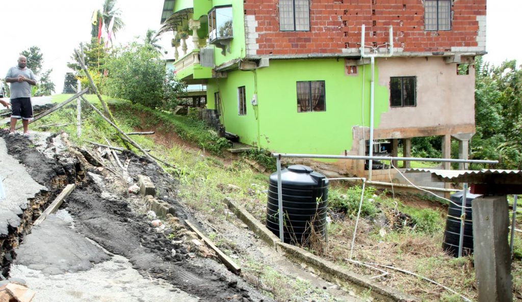 HELP NEEDED URGENTLY: Taradath Bridgemohan looks at the landslip which is threatening his home and those of his neighbours at Sadarath Road, Princes Town.   PHOTO BY VASHTI SINGH