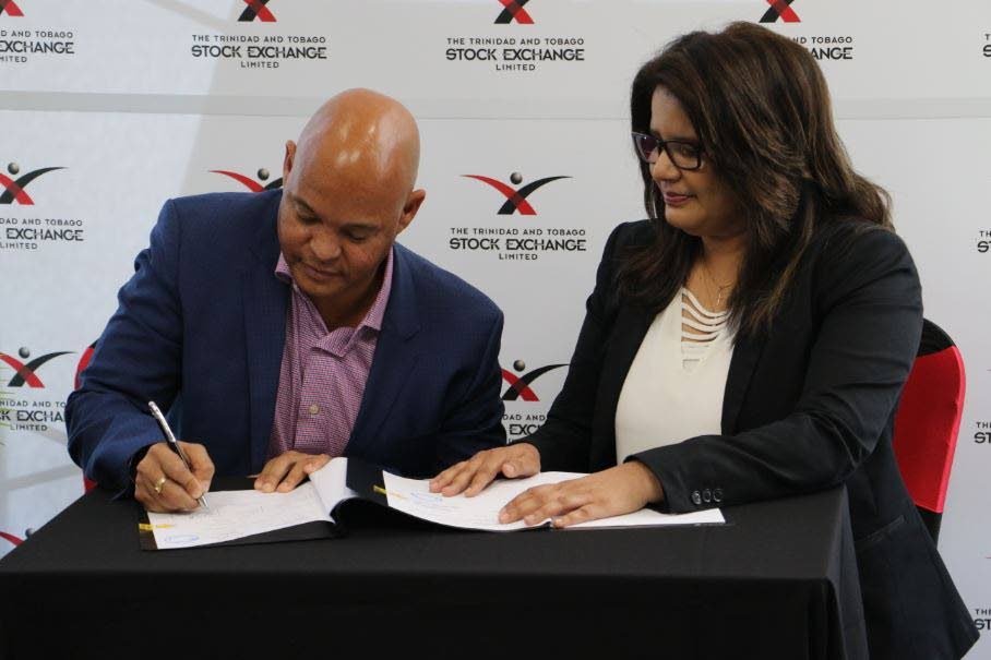 Chairman of CinemaONE Brian Jahra and CEO of the TT Stock Exchange Michelle Persad signs the listing agreement that placed  CinemaONE on the stock exchange. PHOTO: Ornella Mitchell