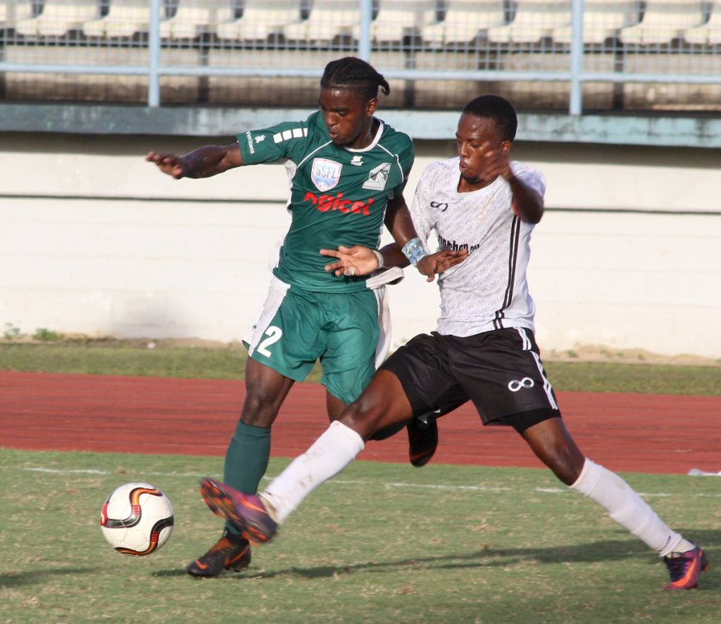 Tyrell Cameron of San Juan North, left, tries to get around Trinity East's captain Randy Jackson in the Coca Cola East Zone Intercol final yesterday at the Larry Gomes Stadium, Arima. 