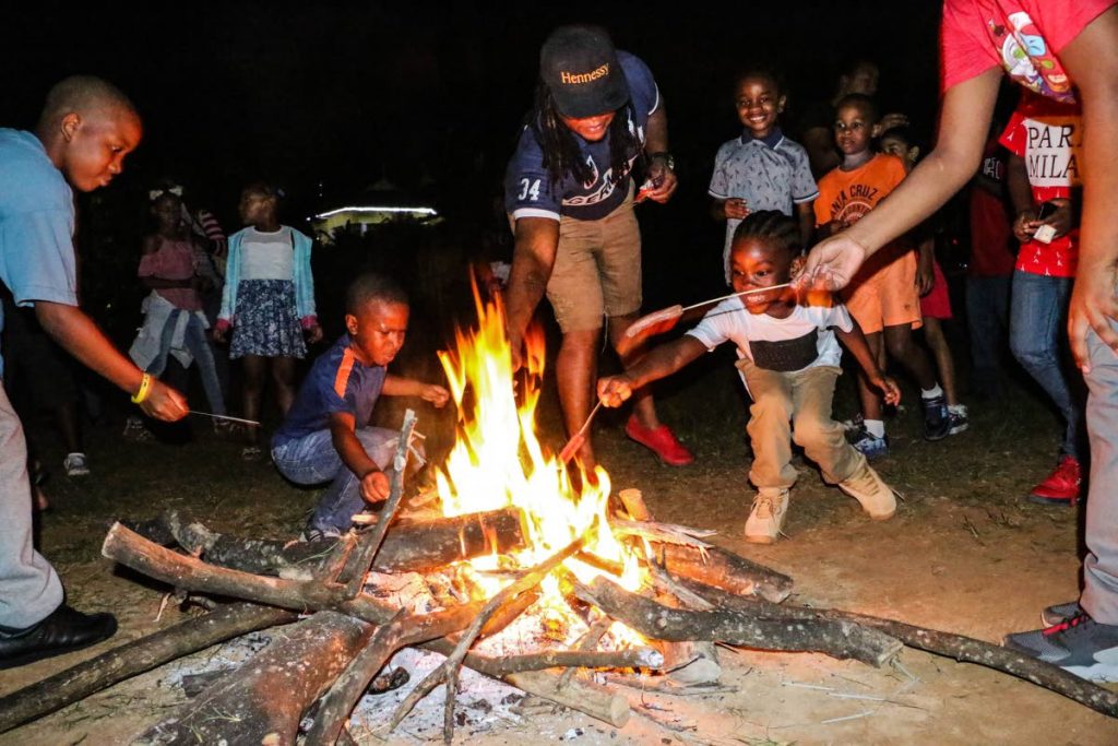 Parents and students of Athenian Pre-Secondary School roast marshmallows and hotdogs on a bonfire at the St Augustine school on November 17. PHOTOS BY RHIANNA Mc KENZIE