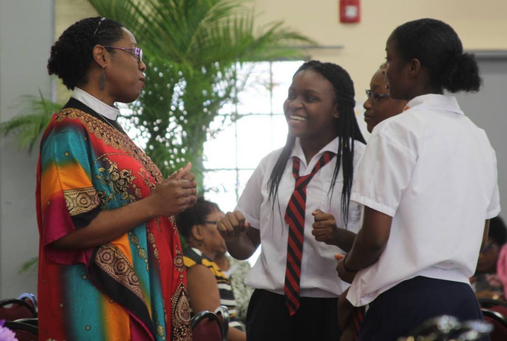 The Very Reverend Shelly-Ann Tenia, dean and rector of Holy Trinity Cathedral, speaks with students Lyse Sealy, from left, Jasmine Cumberbatch and Jada Browne at the St Mary's Anglican Parish Hall, Tacarigua during a stop violence against women breakfast meeting yesterday. PHOTO BY ENRIQUE ASSOON