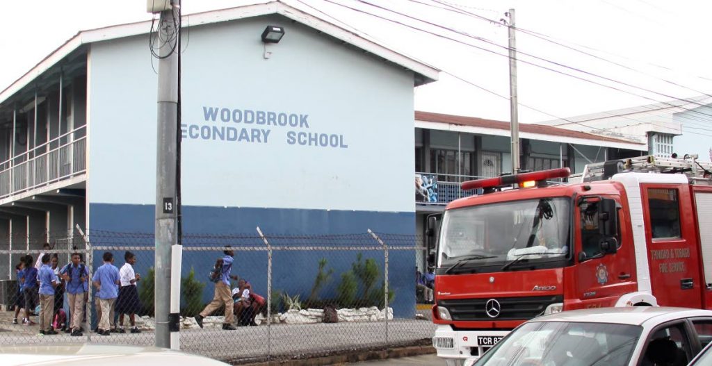 A fire truck parked outside the Woodbrook Secondary School yesterday after a mini-tornado damaged part of the school’s roof.