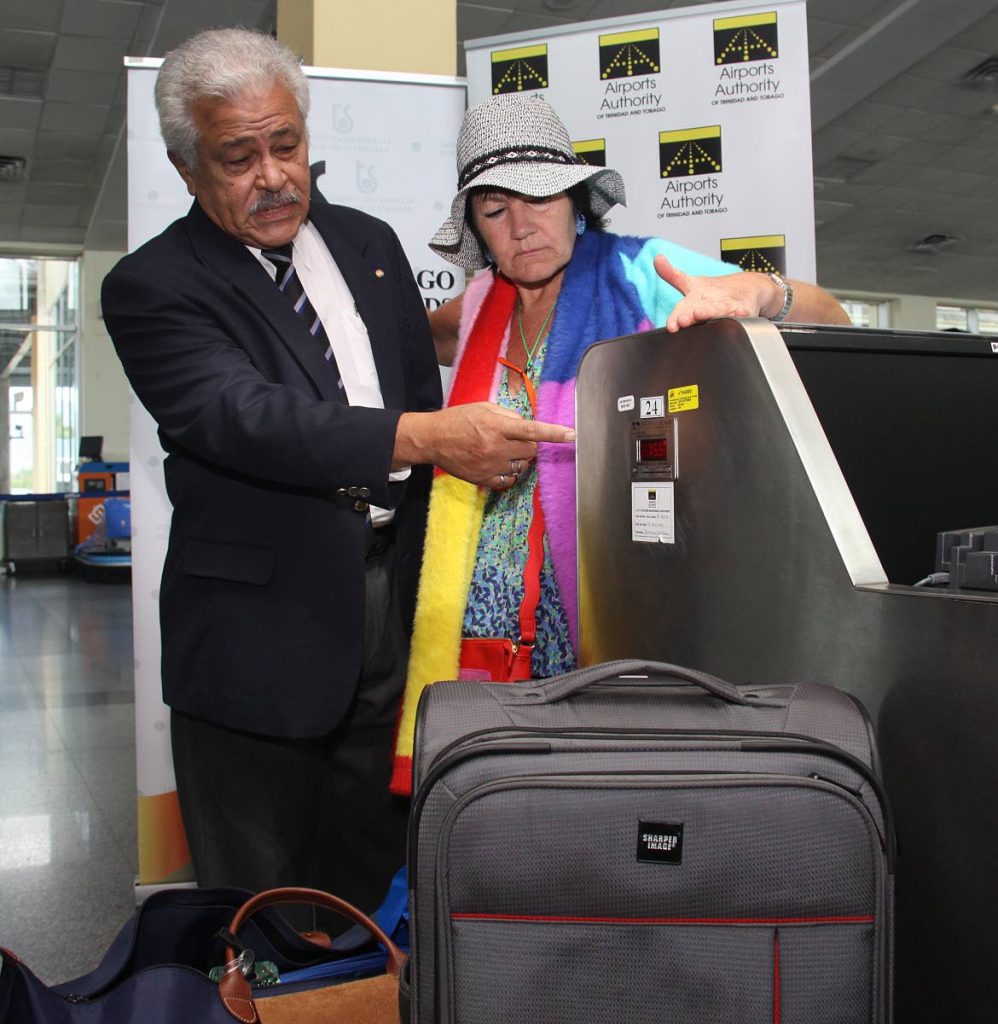 WEIGHT CHECK: TT Bureau of Standards chairman Lawford Dupres assists London-bound passenger Lizzie Gordon with verifying the weight of her luggage at the Piarco airport on Wednesday.