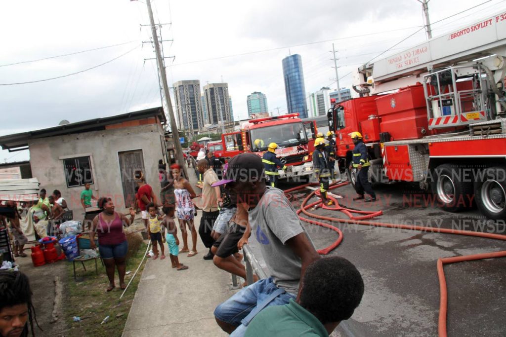 Residents of Sea Lots Port of Spain  looks on in shock after several houses were destroyed in a fire leaving 12 families displaced. PHOTO SUREASH CHOLAI