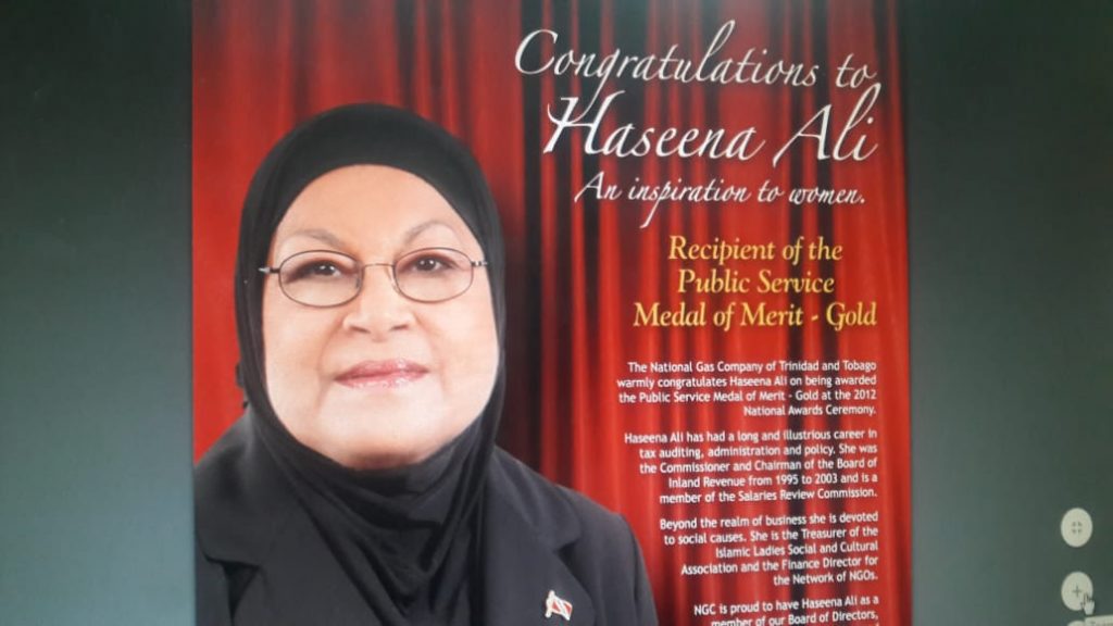  A poster of an advertisement by the National Gas Company congratulating Haseena Ali on her Public Service Medal of Merit award in 2012.