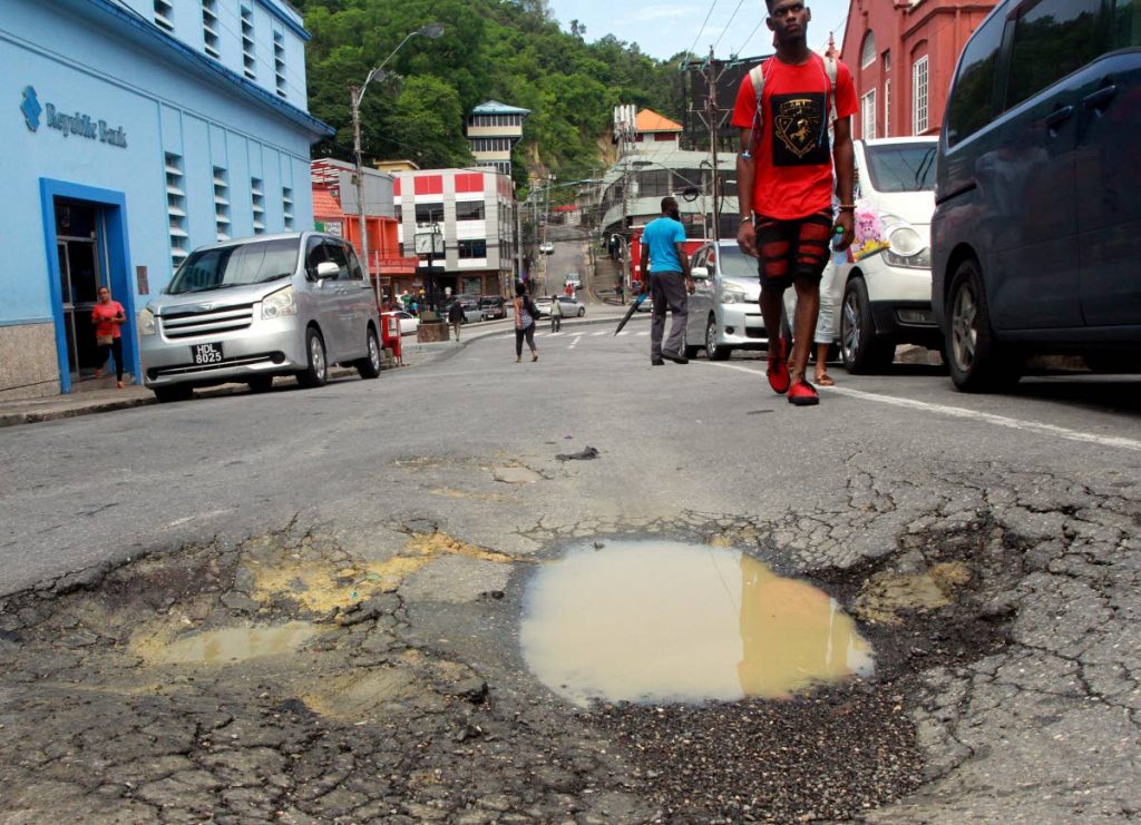 A pedestrian walks past a huge pothole near Library Corner, San Fernando in this July 3, 2018 file photo.
PHOTO BY ANIL RAMPERSAD.