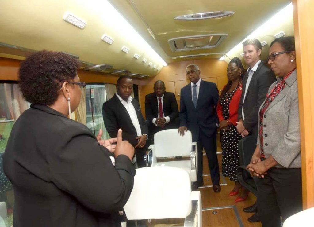 Donna Scoon-Moses, acting CEO, YTEPP, left, points out features of the mobile cosmetology training bus following the signing of a MOU between BPTT and YTEPP. From left are  Jesse Mose, deputy chairman, YTEPP; Minister in the Ministry of Education Dr Lovell Francis; Minister of Education Anthony Garcia; Dr Joan Spence, YTEPP Board member; William Blomfield, Acting Deputy High Commissioner, Australia; and Ronda Francis, corporate responsibility manager, BPTT.