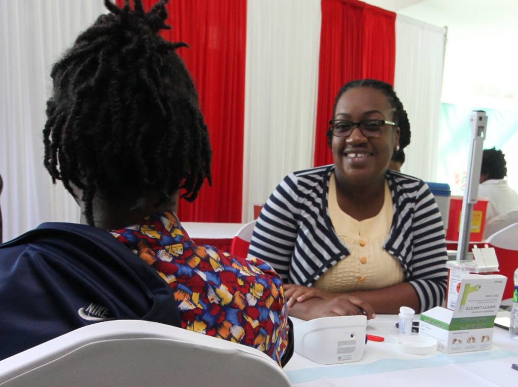 Nursing assistant Genelle Bentham interviews a woman during the outreach exihibition for World Aids Day, Atrium, Piarco International Airport on Friday. PHOTO BY ROGER JACOB.